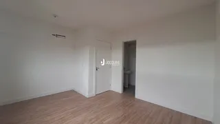 Ambiente interno de uma sala com piso de madeira e paredes brancas.