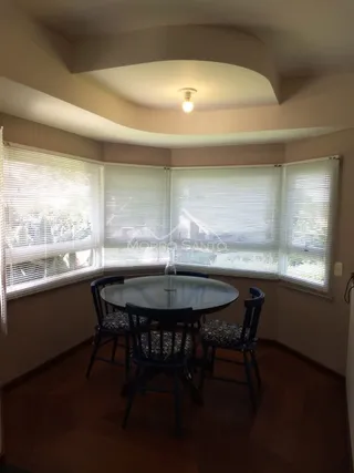 Uma sala de jantar com mesa redonda e janelas cobertas por persianas.