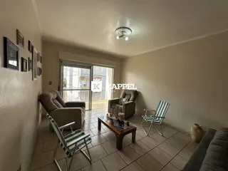 Sala de estar com sofá e poltronas em um ambiente claro com piso de cerâmica.