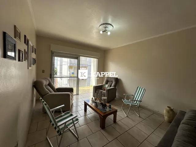 Sala de estar com sofá e poltronas em um ambiente claro com piso de cerâmica.