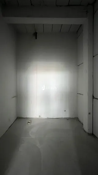 Foto de um interior vazio com paredes brancas e teto exposto.