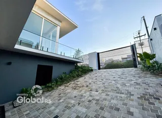 Vista da fachada de uma residência com muro e portão de ferro.