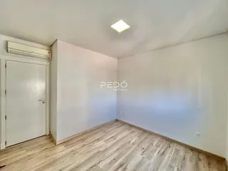 Uma sala interna com piso de madeira clara e paredes brancas.