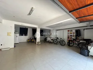 Ambiente interno de uma sala de estar ampla com piso de cerâmica clara.