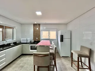 Interior de uma cozinha com área de jantar e armários brancos.