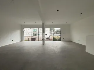Espaço interno amplo com paredes brancas e piso cinza.