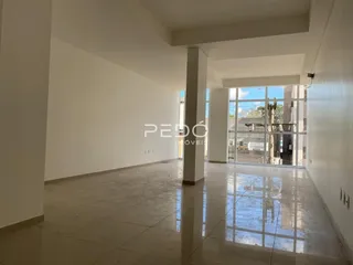 Espaço interno amplo com paredes brancas e piso de concreto.