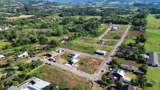 Vista aérea de uma propriedade rural com campos verdes e vegetação densa.