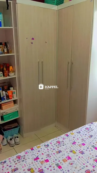 Quarto com armários de madeira clara e cama visível.