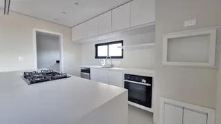 Vista da cozinha moderna com armários brancos e bancada clara.