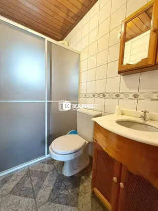 Foto de um banheiro com revestimento de azulejos brancos e um vaso sanitário.
