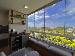 Sala de estar com grande janela oferecendo vista panorâmica da paisagem verde.