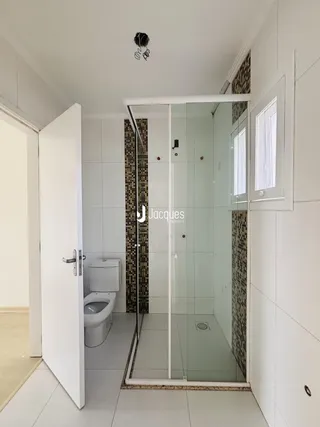 Banheiro com box de vidro e vaso sanitário em um imóvel.