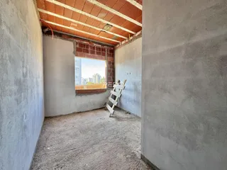 Interior de um espaço com paredes de concreto aparente e teto de telha.