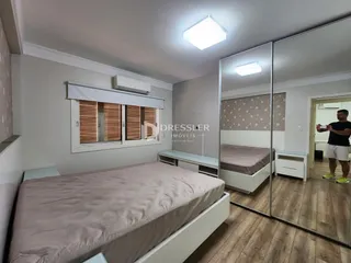 Quarto com cama e espelho refletindo o ambiente interno.
