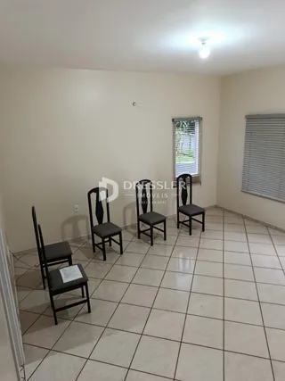 Interior de uma sala com piso de cerâmica e cadeiras escuras.