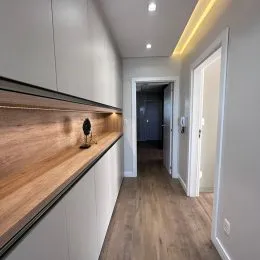 Corredor interno com piso de madeira e painéis de madeira.