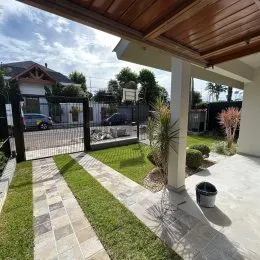 Vista externa mostrando um jardim com grama e calçamento de pedras.