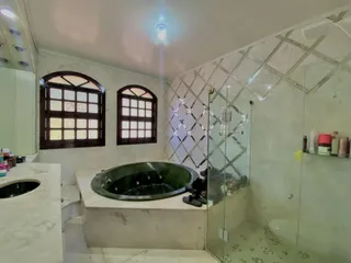 Banheiro com banheira de imersão e box de vidro em ambiente de mármore.
