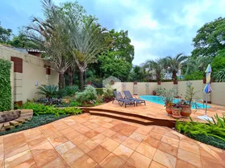 Vista externa de uma área de lazer com piscina e jardim.