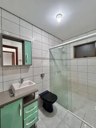 Foto de um banheiro com box de vidro e revestimento cerâmico.