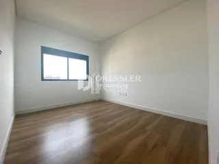 Uma sala com piso de madeira e janela iluminada.