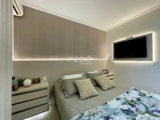 Quarto moderno com cabeceira iluminada e televisão na parede.