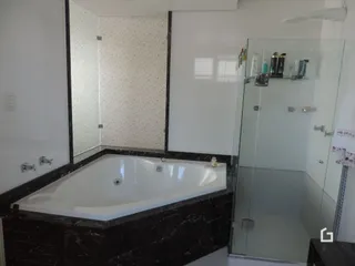 Foto de um banheiro com banheira e box de vidro transparente.