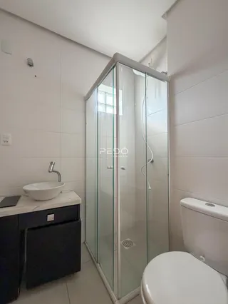 Foto de um banheiro com box de vidro e louças brancas.