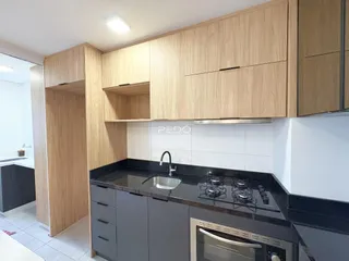 Vista da cozinha moderna com armários de madeira clara e bancadas escuras.