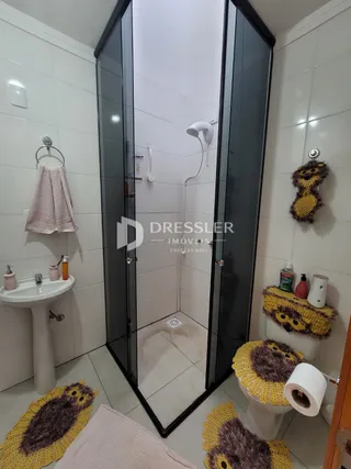 Foto de um banheiro com revestimento branco e box de vidro.