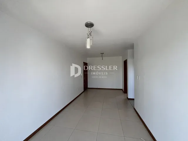 Corredor interno de uma residência com paredes brancas e piso claro.