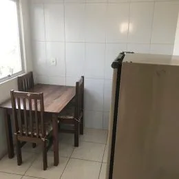 Foto de uma sala de jantar com mesa de madeira e cadeiras em um ambiente claro.