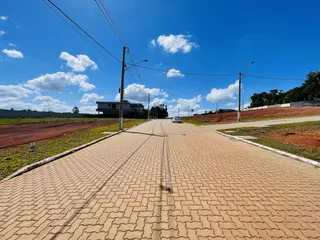 Uma estrada pavimentada se estende por uma área de terra vermelha sob um céu azul.