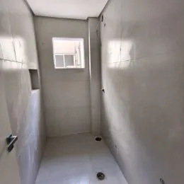 Corredor interno com paredes brancas e piso claro.
