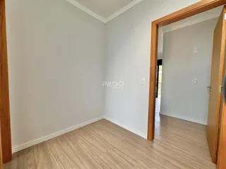 Interior de um ambiente com paredes brancas e piso de madeira clara.