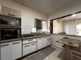 Cozinha com armários brancos e bancada de pedra na área interna do imóvel.