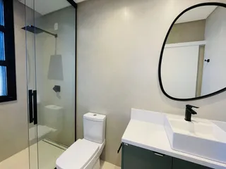 Banheiro moderno com box de vidro e pia de apoio.