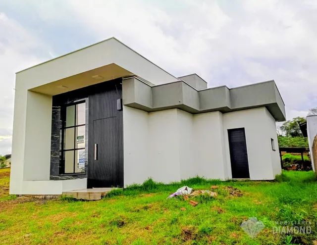 Fachada moderna de uma casa em Lajeado, Brasil, com paredes brancas e portão preto.