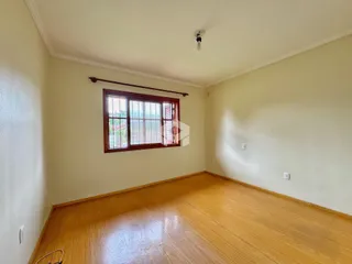 Uma sala de estar com piso de madeira clara e janela.