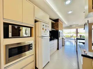 Vista interna de uma cozinha moderna com armários brancos e piso claro.