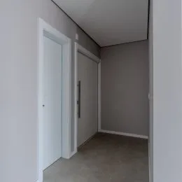 Hall de entrada com paredes brancas e porta branca.