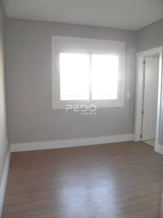 Vista interna de uma sala com piso de madeira e janela.