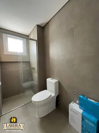 Foto de um banheiro interno com vaso sanitário e box de vidro.