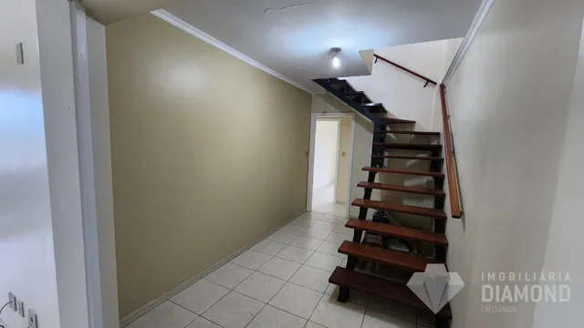 Hall de entrada com piso de cerâmica e escadaria de madeira.