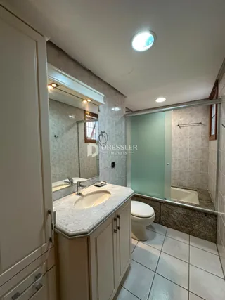 Foto de um banheiro com revestimento cerâmico e box de vidro.
