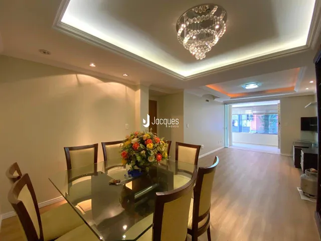Uma sala de jantar com mesa de vidro e cadeiras em um imóvel.