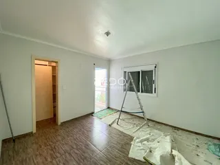 Interior de uma sala com piso de madeira e porta aberta em um imóvel no Brasil.