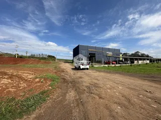 Vista externa de um terreno com uma edificação industrial ao fundo.
