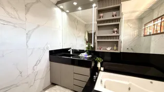 Foto de um banheiro moderno com revestimento de mármore branco e bancada preta.